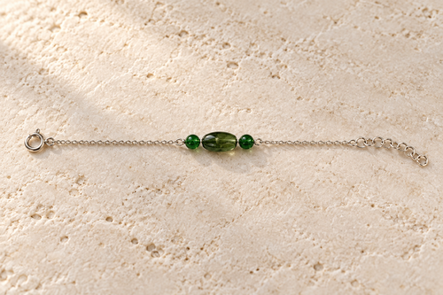 Dark green oval bead with small green round side beads on a silver chain, with clasp and extender.